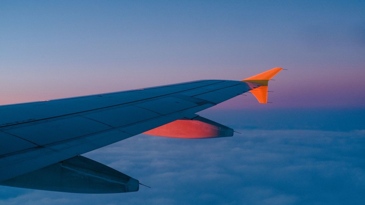 A ZIPAIR-style Boeing 787 long-haul jet flying above clouds at dusk