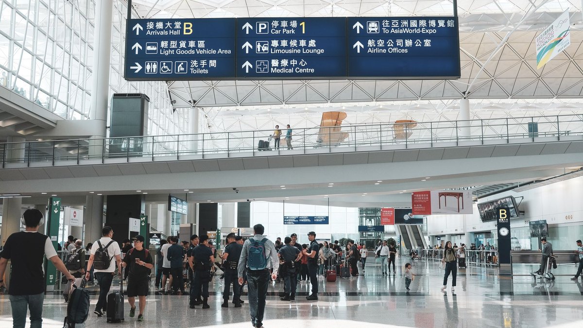 Travellers queue at passport control kiosks in a busy European airport arrivals hall
