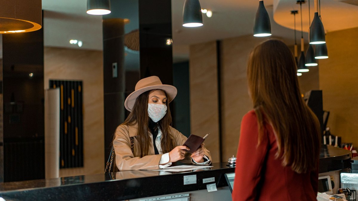 Hotel receptionist reviewing an online booking account on a laptop at the front desk