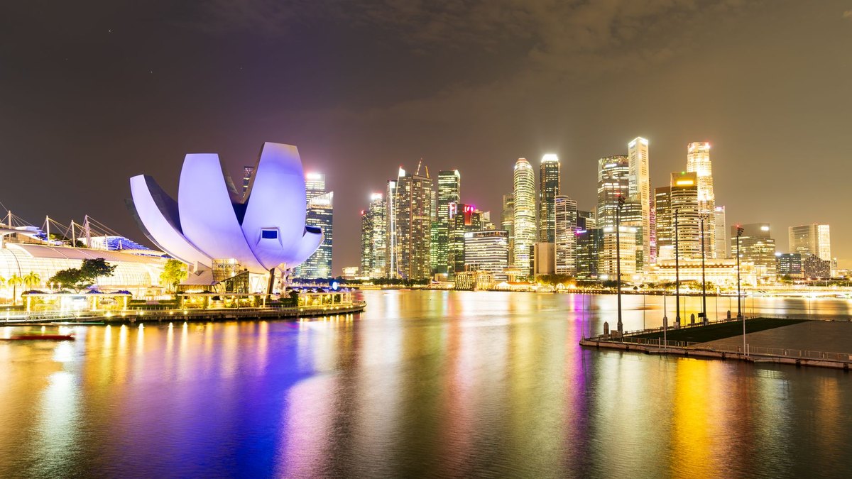 Visitors on the Marina Bay waterfront in Singapore at dusk with the city skyline lit behind them